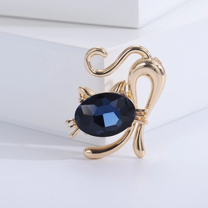 Detailed close-up of a golden cat brooch with a faceted navy blue crystal gemstone
