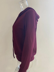 Detalle del tejido de punto acanalado burdeos en una sudadera con capucha de manga larga