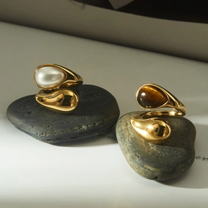 Polished gold stainless steel rings set with white and brown oval gemstones on stones