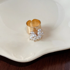 Detail of adjustable gold wide ring with cluster of cream pearls on ceramic tray