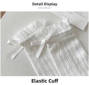 Detail view of white lace socks featuring a delicate ribbon bow and elastic ruffled cuff