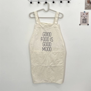 Detail view of cream canvas apron featuring the Good Food Is Good Mood slogan and pocket