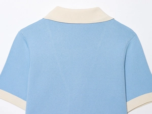 Close-up of sky blue knit polo shirt featuring ivory contrast trim on the collar and back