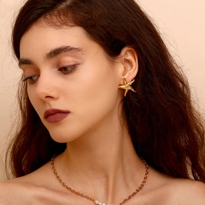 Elegant 18K gold starfish earrings with sparkling crystals and pearl necklace on a model