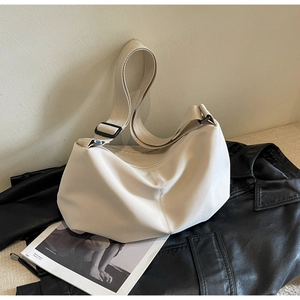 Detailed view of cream nylon crescent tote bag on black leather jacket background