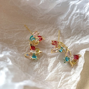 Macro shot of colorful zircon butterfly earrings with gold plating on white paper