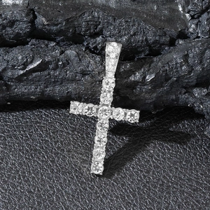 Close-up of silver iced out cross pendant with sparkling stones on dark textured stone