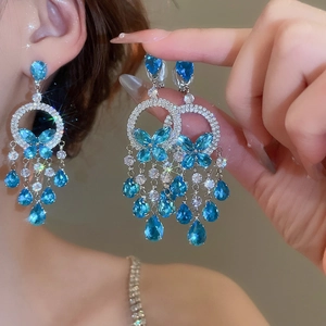 Close-up of elegant zircon butterfly tassel earrings with blue drop-shaped gemstones