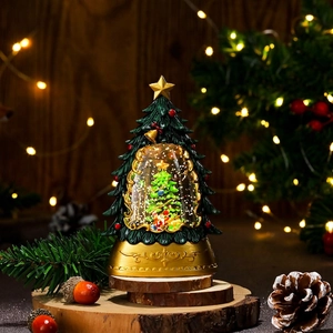 Detail of a glowing Christmas tree lantern with a snow globe scene and golden base decor