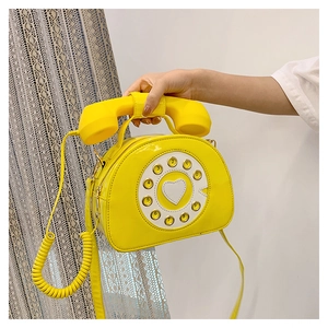 Detail of creative vintage yellow telephone handbag with rotary dial and handset handle
