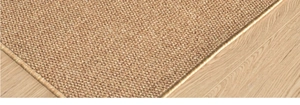 Macro detail of beige woven sisal rug with golden border on light wood flooring