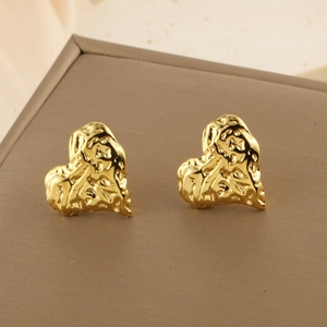 Gros plan de boucles d'oreilles cœur dorées avec texture martelée et éclat métallique