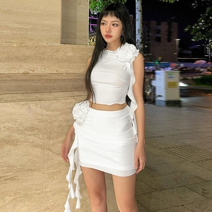 Detail of white two-piece set featuring 3D floral accents and ruffle trim on the skirt