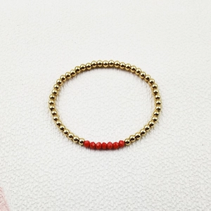 Detailed view of elastic handmade bracelet with golden steel beads and red faceted crystals