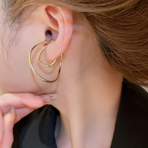 Close-up of elegant gold irregular twisted metal ear cuff on a model side profile
