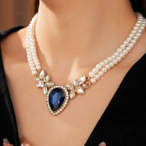 Gros plan d'un collier de perles à double couche avec pierre bleue et pendentif zircon