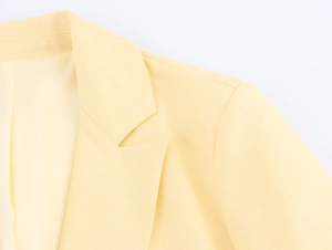 Close-up of lapel and shoulder stitching on a light yellow tailored blazer jacket