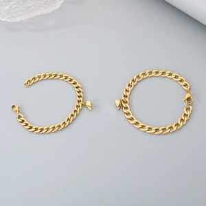 Detailopname van gouden Cubaanse schakelarmbanden met magnetische hartjes op grijs