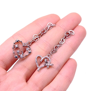Close-up of asymmetric silver heart and butterfly drop earrings with zircon details