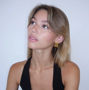 Detailed close-up of a model wearing 18k gold-plated striped trapezoid earrings