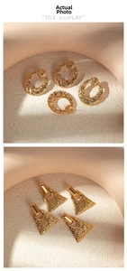 Detailed close-up of golden geometric stud earrings with hammered metal texture