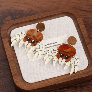 Macro detail of brown acrylic spider earrings on rustic linen background for Halloween