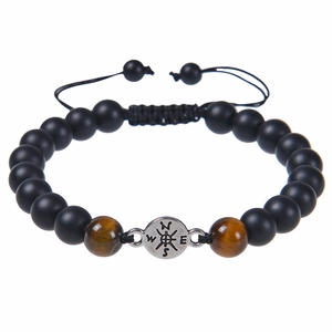 Close-up of matte black beads with tiger eye stones and metal compass charm on braided cord