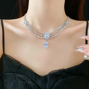 Detail of layered silver necklace with teardrop zircon pendants on model's neckline