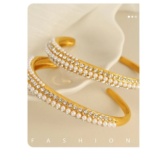 Close-up of golden open bangle with white pearls and sparkling cubic zirconia stones