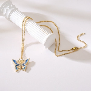 18K gold plated necklace with blue enamel butterfly pendant on white marble pillar