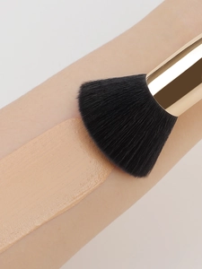 Flat top foundation brush blending liquid foundation smoothly on skin for a flawless finish