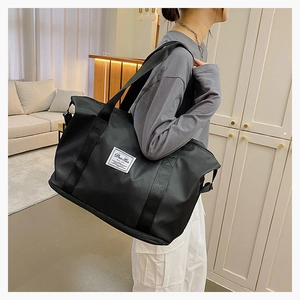Close-up of a large black fitness bag featuring a white brand label and reinforced handles