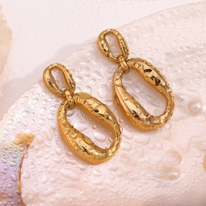 Detailed close-up of double oval geometric gold-plated earrings on a shell background