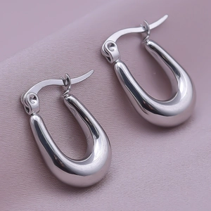 Close-up of polished silver 304 stainless steel U-shaped huggie earrings on silk fabric