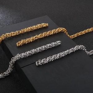 Close-up of gold and silver Byzantine weave chains on a professional black display