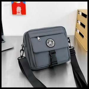 Detail of gray nylon messenger bag with adjustable strap and buckle closure on a desk