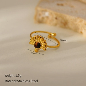 Detail of vintage gold sunburst ring in stainless steel with center brown gemstone inlay