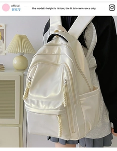 Close-up of beige minimalist backpack featuring braided zipper pulls and side pockets