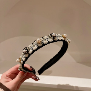 Detail of black headband with white pearls, enamel flowers and sparkling rhinestones