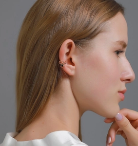 Close-up of golden spider ear cuff with black gemstone on model's ear cartilage