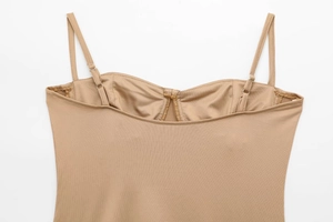 Détail des bretelles réglables et du tissu satiné lisse sur un body beige ajusté