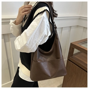 Detail of large dark brown leather hobo bag worn by model for a casual commute
