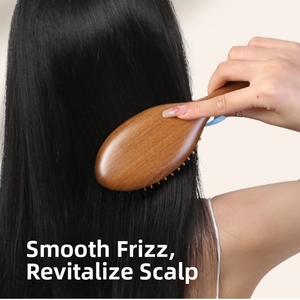 Close-up of a wooden air cushion massage comb smoothing long hair on a model
