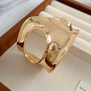 Gros plan du bracelet manchette géométrique doré ajouré dans un coffret à bijoux chic