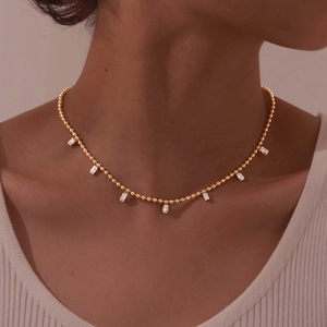 Gold ball chain necklace featuring seven white rectangular zircon stones worn by a model