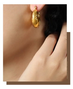 Gros plan d'élégantes boucles d'oreilles cœur dorées avec une finition métal polie