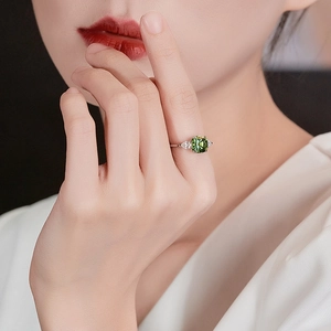 Elegant silver open ring with emerald-cut green stone on model finger