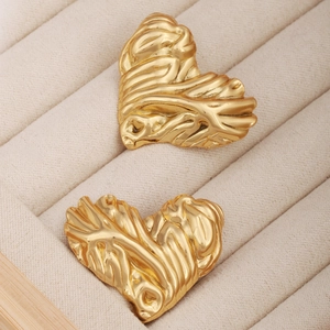 Détails macro des boucles d'oreilles cœur dorées avec finition texture lave et nervures