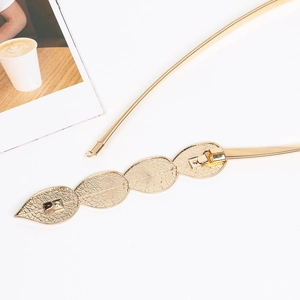 Detail of gold elastic metal chain belt featuring a hollow leaf-shaped metal buckle clasp