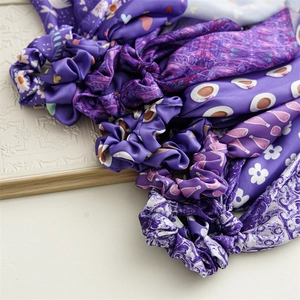 Close-up of assorted purple silk satin hair scarves with floral and heart patterns